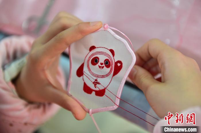 圖為一名小學(xué)生正在繡制2022年北京冬奧會(huì)吉祥物“冰墩墩”形象?！∮髟屏?攝