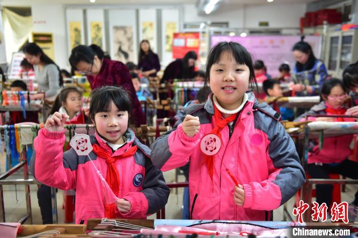 圖為小學(xué)生展示繡制好的2022年北京冬奧會(huì)吉祥物“冰墩墩”形象。　喻云亮 攝