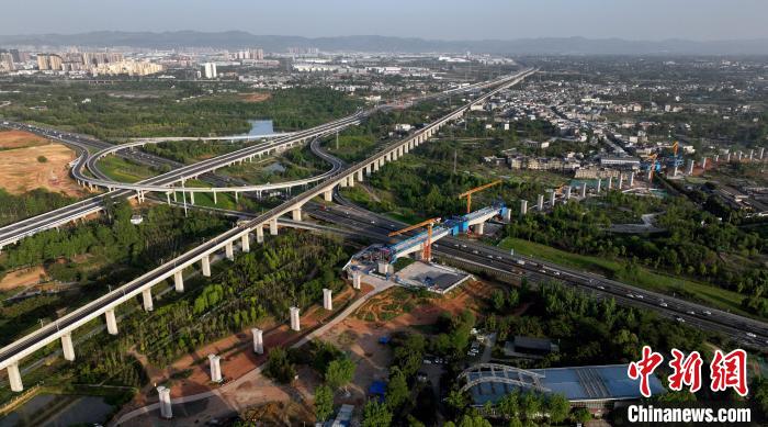 航拍正在建設(shè)的跨越成都繞城高速公路連續(xù)梁施工現(xiàn)場，旁邊依次為已運(yùn)營的成渝高速鐵路和機(jī)場高速公路?！⒅铱?攝