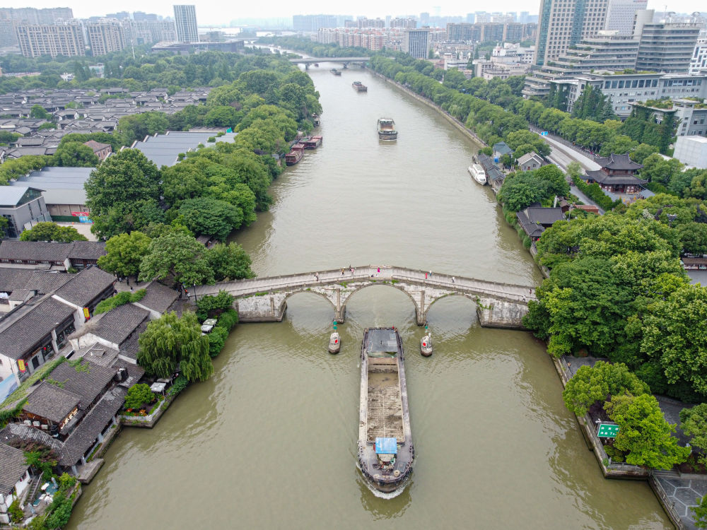 5月27日，一艘貨船駛過(guò)京杭大運(yùn)河南端標(biāo)志建筑杭州拱宸橋。(無(wú)人機(jī)照片)新華社記者江漢 攝