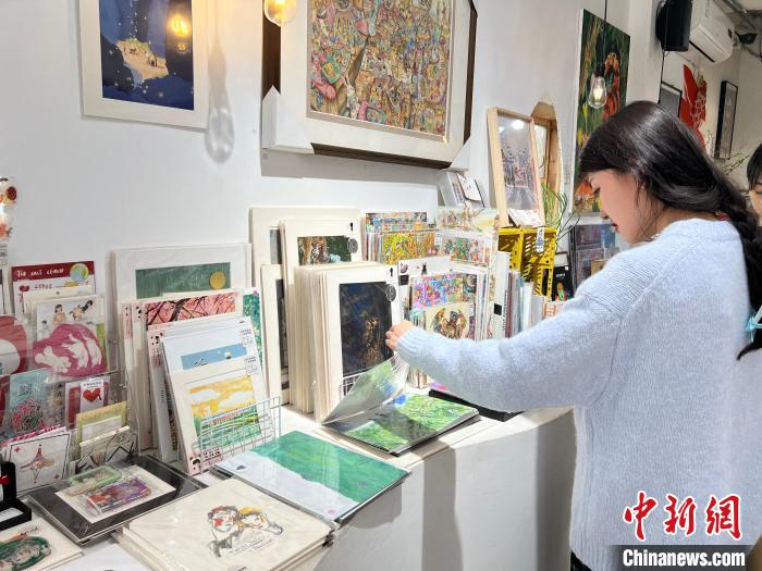 圖為藝術(shù)品商店內(nèi)，顧客挑選插畫作品?！＄婌?攝