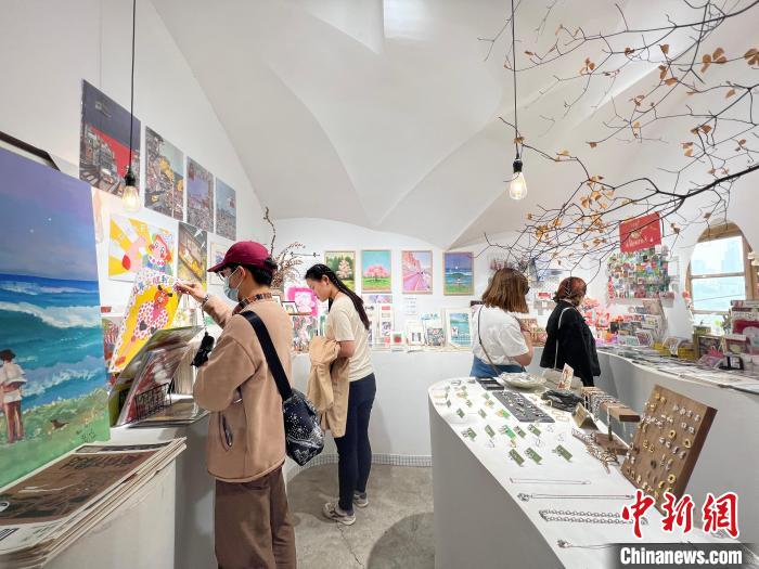 圖為藝術(shù)品商店內(nèi)，顧客挑選插畫作品?！＄婌?攝
