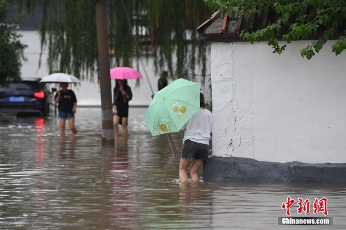 7月31日，市民行走在雨中的北京房山區(qū)瓦窯頭村。北京市氣象臺當日10時發(fā)布分區(qū)域暴雨紅色預(yù)警信號。北京市水文總站發(fā)布洪水紅色預(yù)警，預(yù)計當日12時至14時，房山區(qū)大石河流域?qū)⒊霈F(xiàn)紅色預(yù)警標準洪水。<a target='_blank' href='/'><p  align=