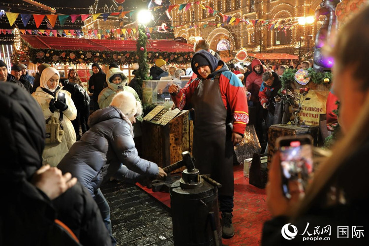游客在新年集市上體驗(yàn)制作紀(jì)念幣。人民網(wǎng)記者 隋鑫攝