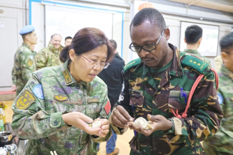 圖為維和官兵與外軍人員共同包餃子。胡光明攝