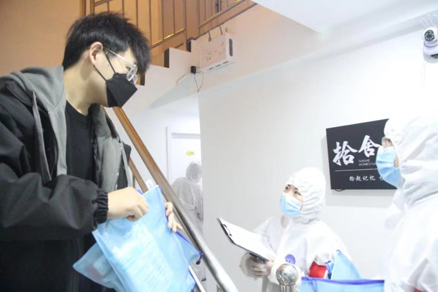 社區(qū)工作人員和志愿者身穿防護服上門送馬應龍大健康防疫包。徐帥攝