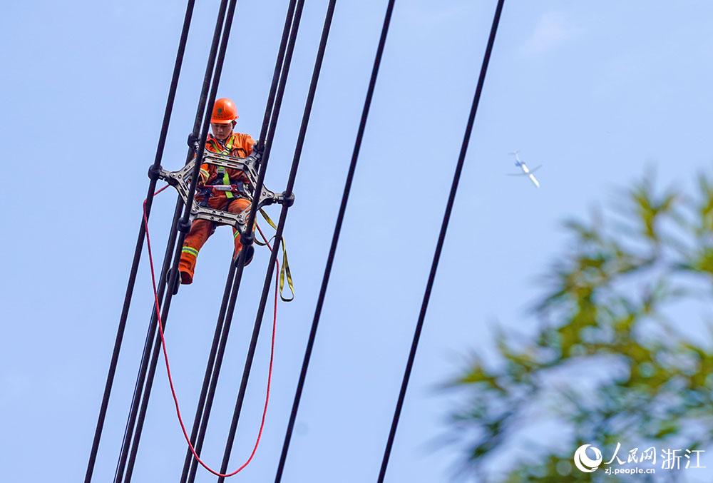 3月11日，在浙江省諸暨市河上鎮(zhèn)，浙江省送變電工程有限公司檢修人員在高空的導線上進行線路檢修維護。人民網(wǎng) 章勇濤攝