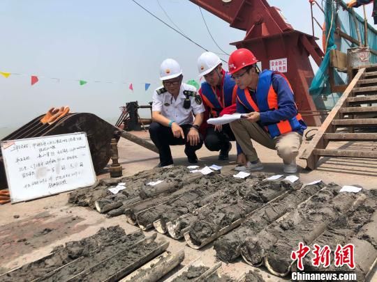 圖為勘察設(shè)計人員與海事局工作人員查看巖芯情況?！∥赫?攝