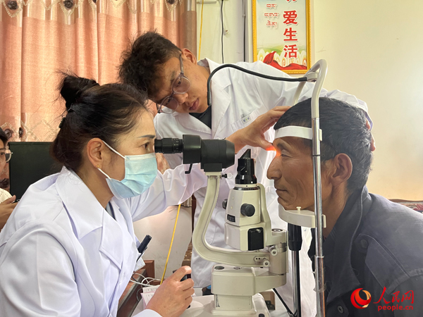 王紅英（左）和團(tuán)隊(duì)成員為達(dá)熱村村民檢查眼睛。人民網(wǎng)記者 杜燕飛攝