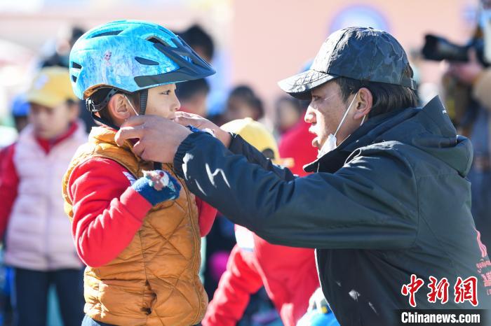圖為拉薩市實(shí)驗(yàn)幼兒園孩子在教練的幫助下穿戴頭盔?！『闻罾?攝