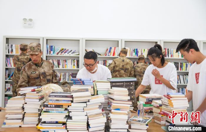 圖為志愿者們和邊防戰(zhàn)士整理圖書?！詵| 攝