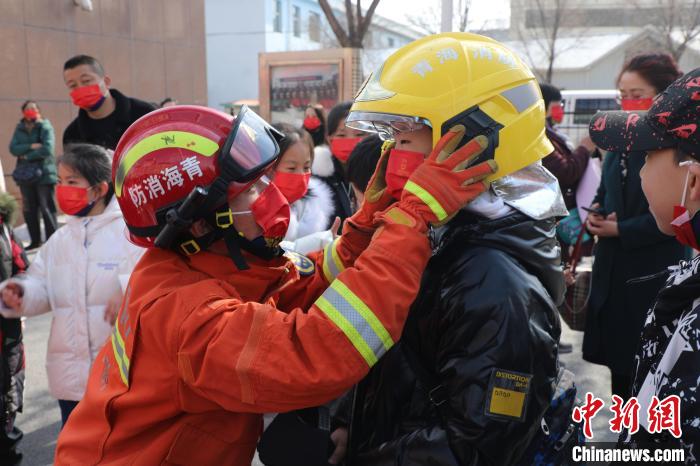 圖為小朋友體驗(yàn)試穿消防滅火防護(hù)服。　楊龍建 攝