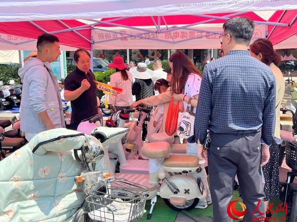 某電動自行車品牌工作人員向消費者介紹以舊換新相關情況。人民網(wǎng)記者 杜燕飛攝