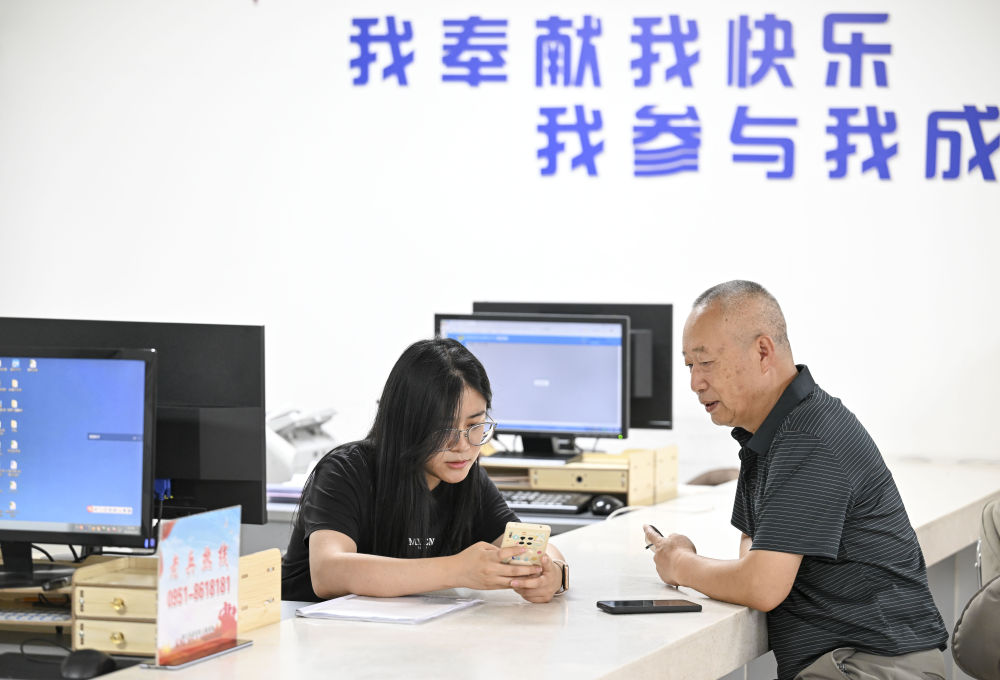 2024年6月20日，在寧夏銀川市金鳳區(qū)長城花園社區(qū)黨群服務(wù)中心，工作人員幫助居民辦理業(yè)務(wù)。圖片來源 新華社