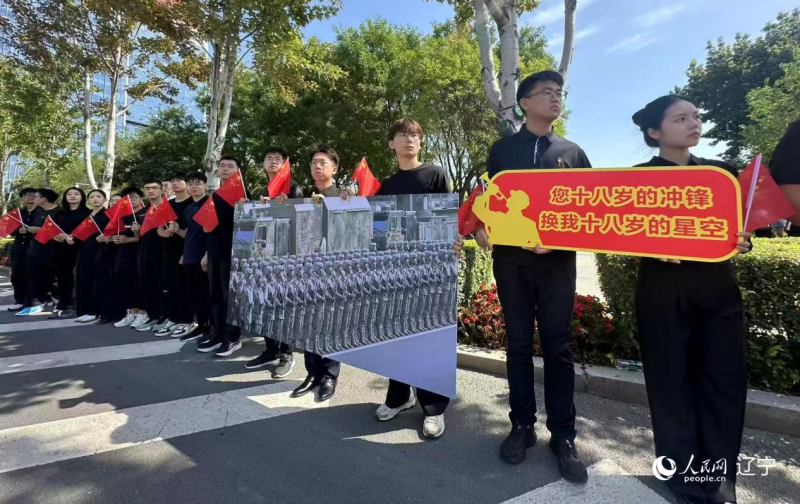 沈陽市人民廣場上，大學生們手持閱兵的圖片，告慰英烈。人民網記者 周頌雪攝
