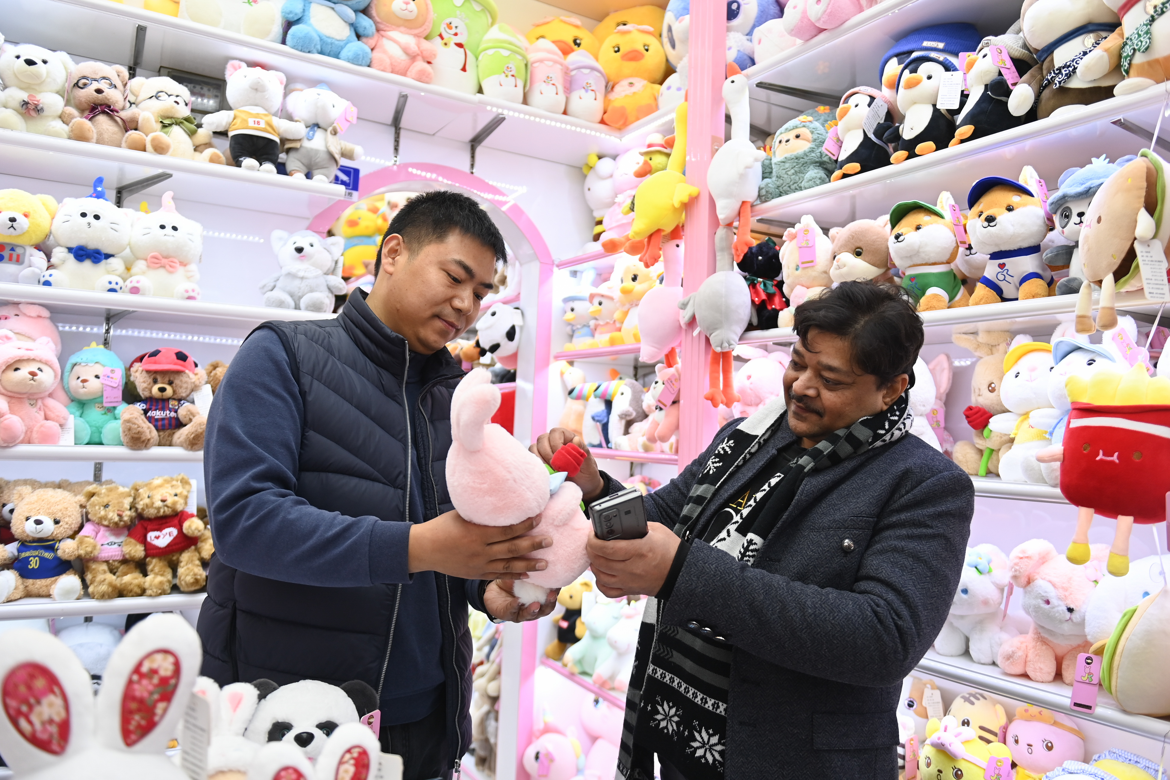 2023年2月2日，來自印度的客商（右）在義烏國(guó)際商貿(mào)城的一家玩具店鋪內(nèi)選購(gòu)。