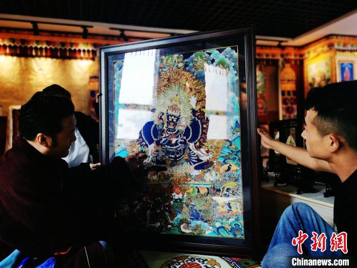 圖為久美尖措(左)與徒弟們展示唐卡作品?！?zhí)砀?攝