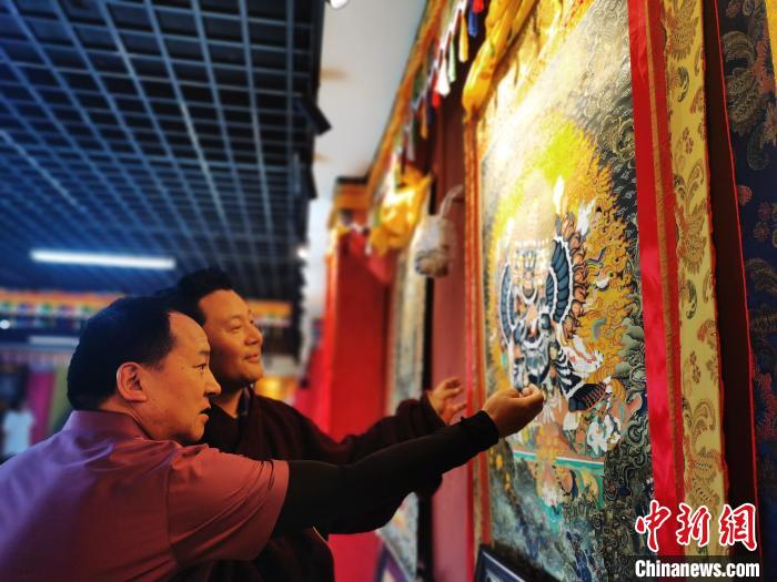 圖為久美尖措展示唐卡作品?！?zhí)砀?攝