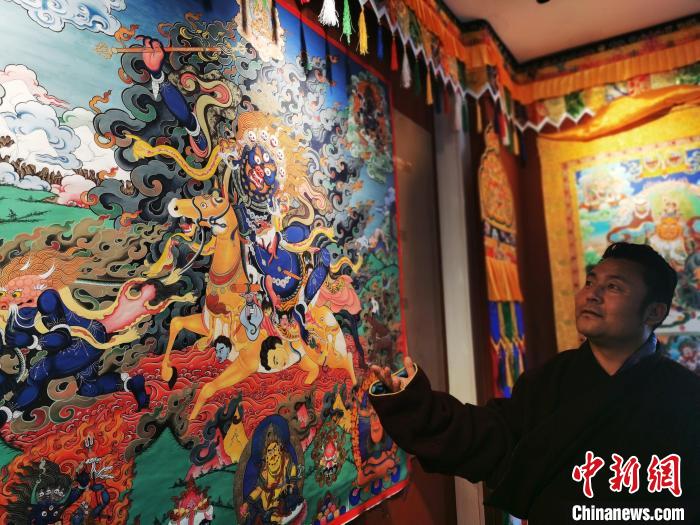 圖為久美尖措展示唐卡作品?！?zhí)砀?攝