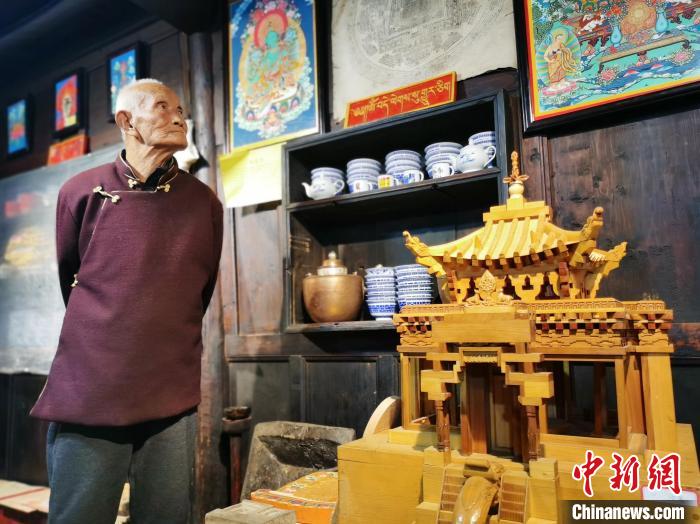 圖為古堡內(nèi)的藝人桑杰展示自己的雕刻作品?！?zhí)砀?攝