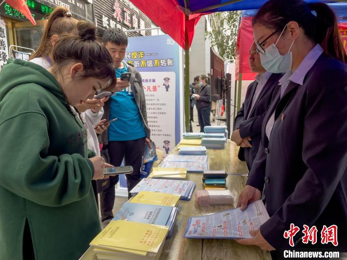 圖為工作人員正在向路過市民介紹國家反詐中心軟件的功能?！≈x牧 攝