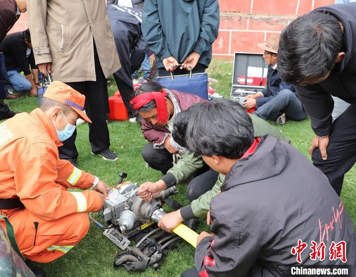 圖為森林消防員為護(hù)林員講解滅火裝備的使用方法?！〔际猩窒乐ш?供圖
