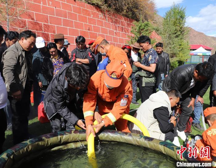 圖為森林消防員為護(hù)林員講解滅火裝備的使用方法?！〔际猩窒乐ш?供圖