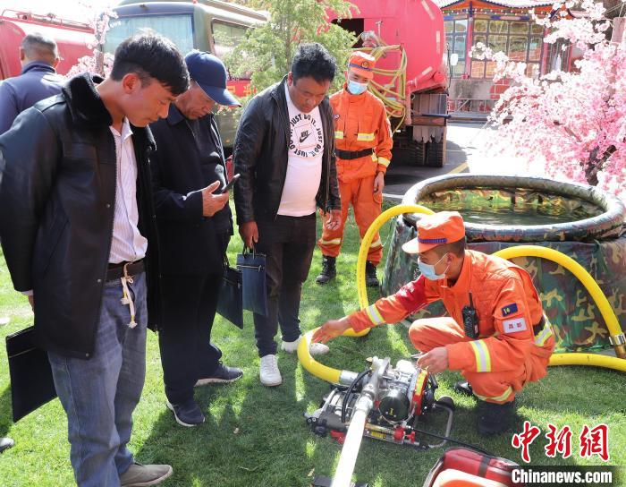圖為森林消防員為護(hù)林員講解滅火裝備的使用方法?！〔际猩窒乐ш?供圖