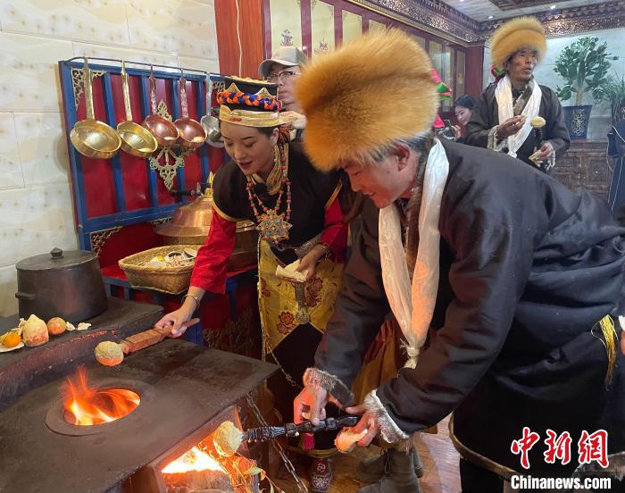 圖為人們在火上烤節(jié)日美食“結達”?！∪轿木?攝