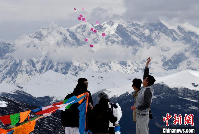 圖為5月14日，游客在西藏林芝色季拉山觀景臺拋灑“隆達(dá)”(風(fēng)馬旗，藏族民眾的一種祈福方式)。　李林 攝