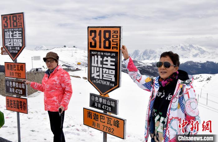 圖為5月14日，西藏林芝色季拉山觀景臺，游客與南迦巴瓦峰合影。　李林 攝